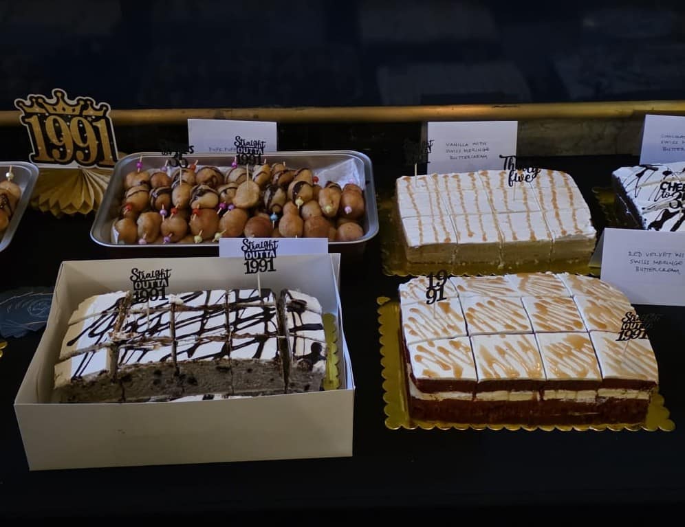 A catered dessert table with cake slices and puff-puff platters